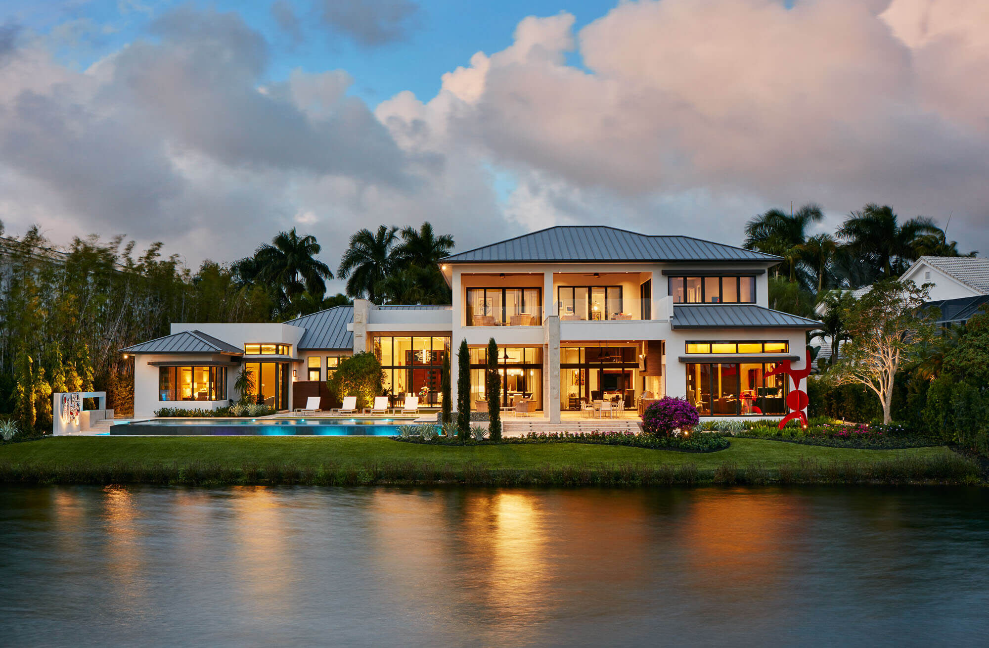 Waterfront estate glowing at dusk, reflected in the lake