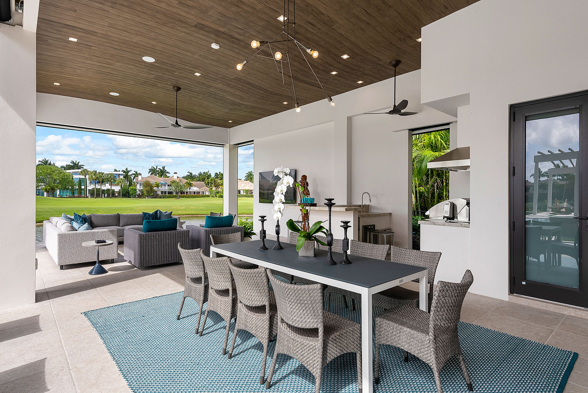 Covered outdoor dining terrace with a wood ceiling and woven chairs