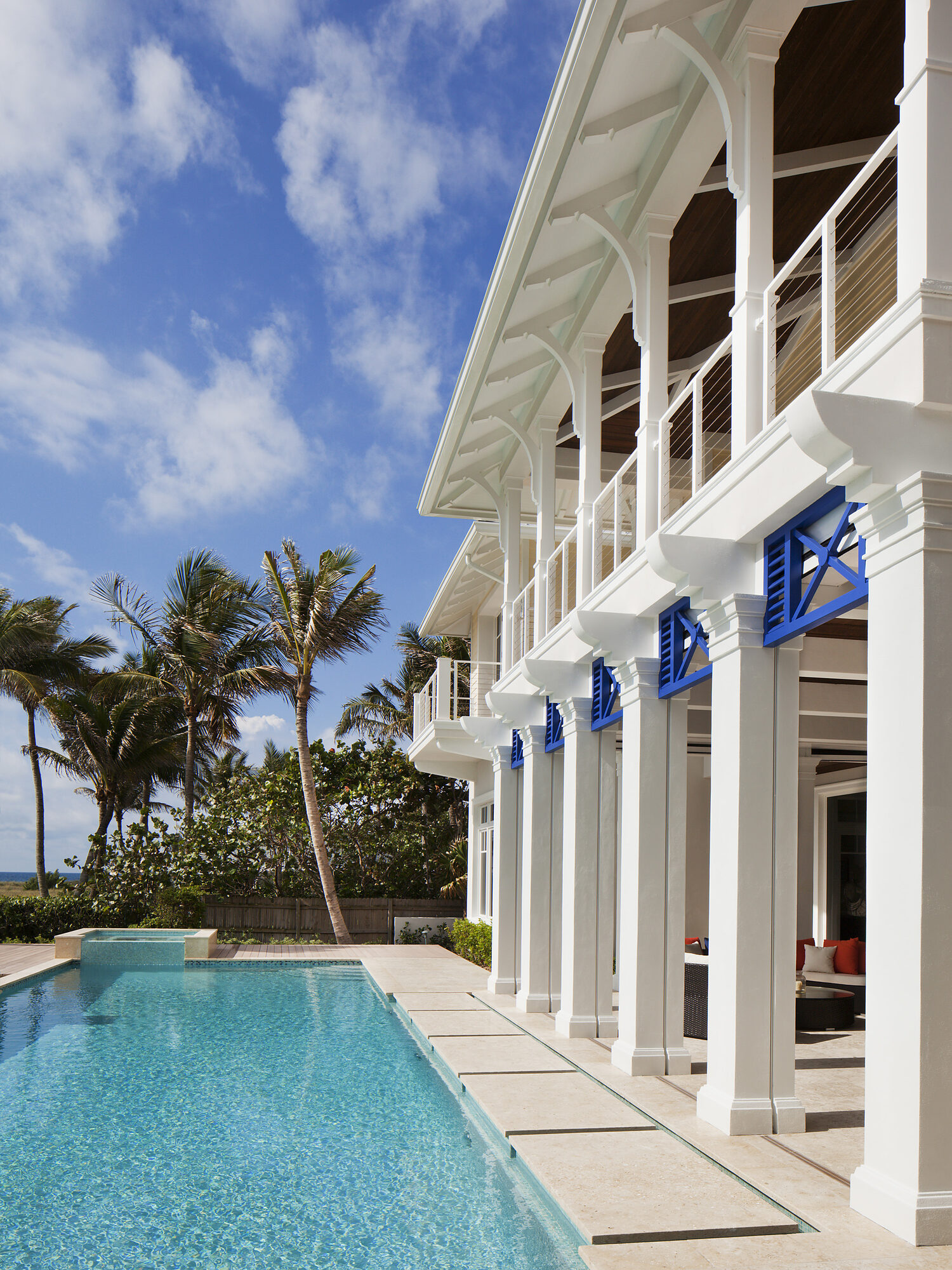 White colonnaded residence with blue shutters beside a pool